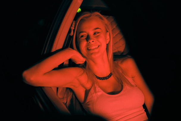 Una hermosa chica de aspecto europeo se sienta en el asiento del pasajero en el coche y mirando a la ventana - Foto, imagen