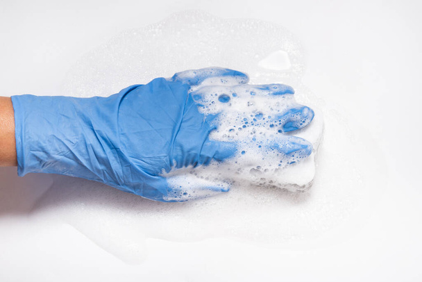 Hand with foam holding sponge, cleaning white surface - Foto, Imagen