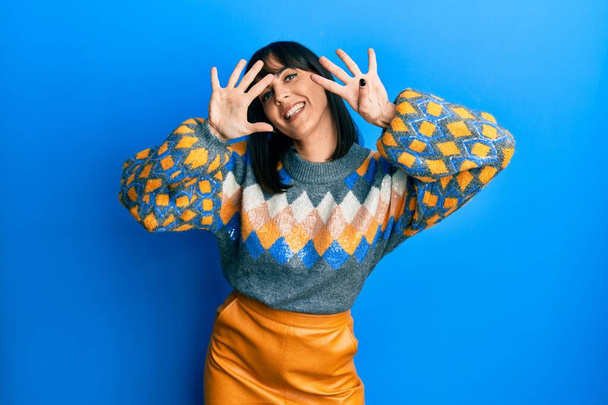 Mujer hispana joven vistiendo suéter casual de invierno mostrando y señalando con los dedos número nueve mientras sonríe confiada y feliz.  - Foto, Imagen