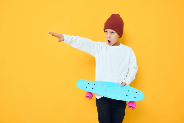 Cool smiling boy with red backpack blue skateboard studio posing - Photo, Image