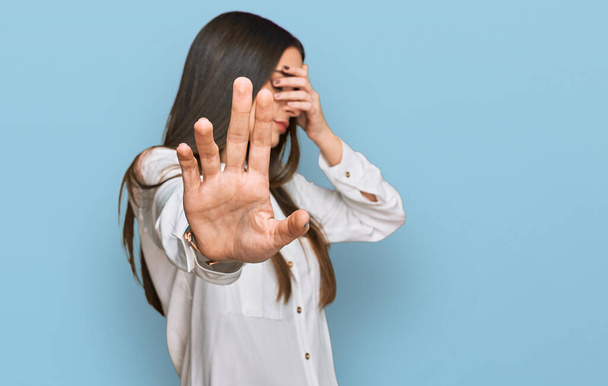 Young beautiful woman wearing casual white shirt covering eyes with hands and doing stop gesture with sad and fear expression. embarrassed and negative concept.  - Foto, immagini