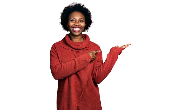 Африканська американка з волоссям афроамериканського кольору, одягнена в білизну, була вражена і посміхається перед камерою, показуючи пальцем..  - Фото, зображення