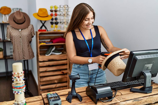 Молодая латиноамериканка улыбается уверенно работая в магазине одежды - Фото, изображение