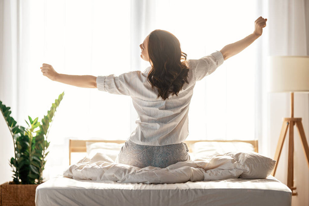 Happy young woman enjoying sunny morning on the bed.      - Фото, зображення