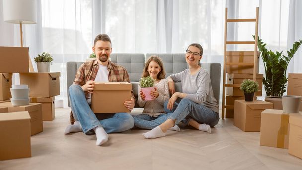 Happy young family are moving to new apartment. Parents and daughter with boxes. - Foto, Bild