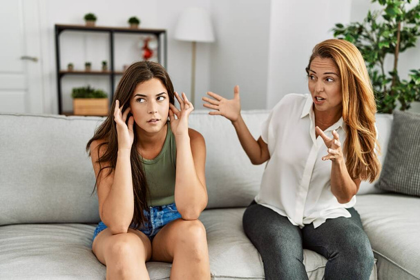 Мати і дочка нещасливі сперечаються, сидячи на дивані вдома
 - Фото, зображення