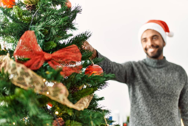 Giovane africano americano uomo sorridente felice decorazione albero di Natale a casa. - Foto, immagini