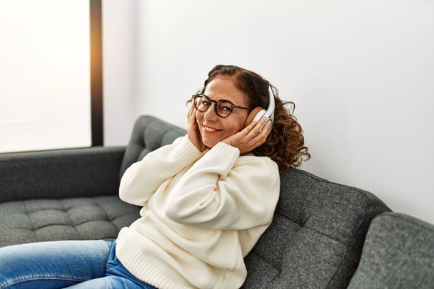 Middle age hispanic woman smiling confident listening to music at home - Photo, Image