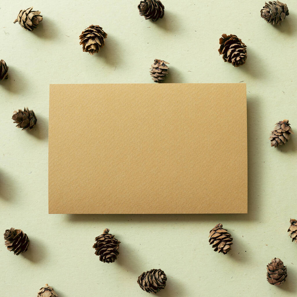 Bloc de notas en blanco con conos de pino sobre fondo verde caqui. concepto de otoño e invierno - Foto, imagen