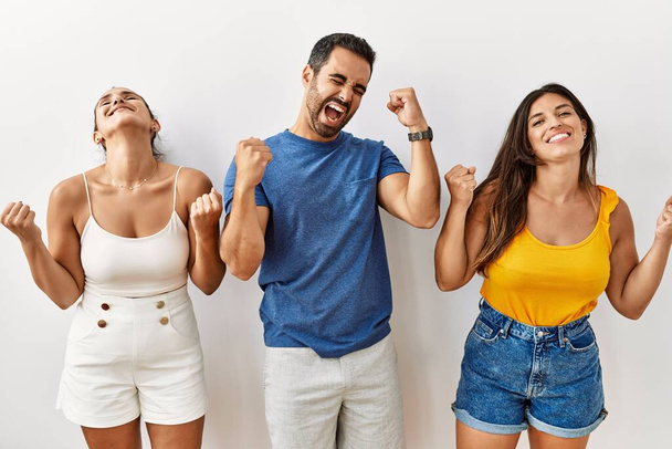 Group of young hispanic people standing over isolated background celebrating surprised and amazed for success with arms raised and eyes closed. winner concept.  - Fotoğraf, Görsel