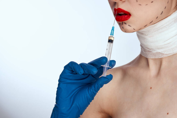 beautiful woman in blue gloves syringe in hands contour on the face lifting light background - Fotografie, Obrázek