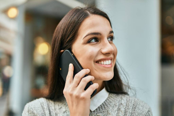 Joven mujer hispana sonriendo feliz hablando en el smartphone de la ciudad. - Foto, imagen