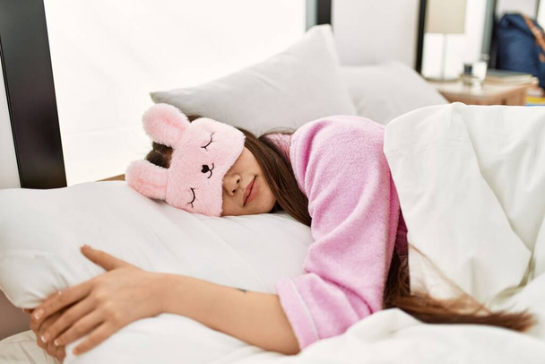 Young chinese girl wearing funny sleep mask sleeping on the bed at bedroom. - Photo, Image