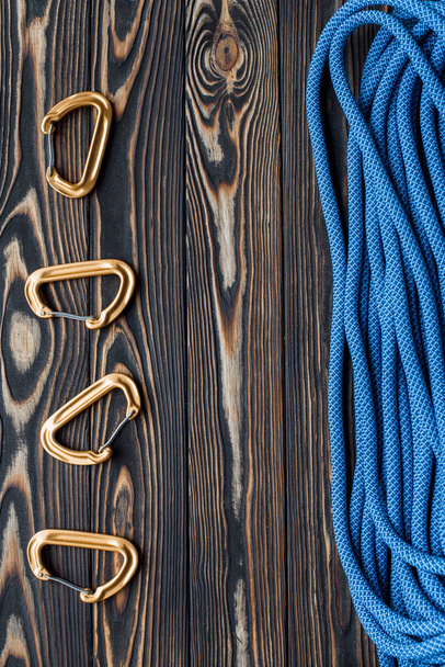 Tools on the left and cable on the right side. Isolated photo of climbing equipment. Part of carabiner lying on the wooden table. - Zdjęcie, obraz