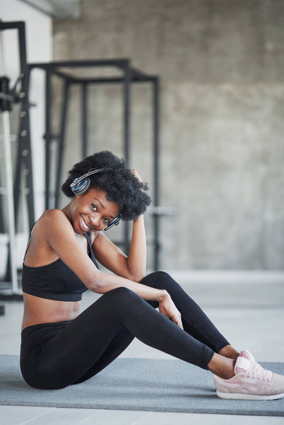 Happy girl. African american woman with curly hair and in sportive clothes have fitness day in the gym. - Zdjęcie, obraz
