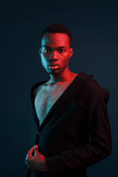 Confident and serious. Futuristic neon lighting. Young african american man in the studio. - Foto, imagen