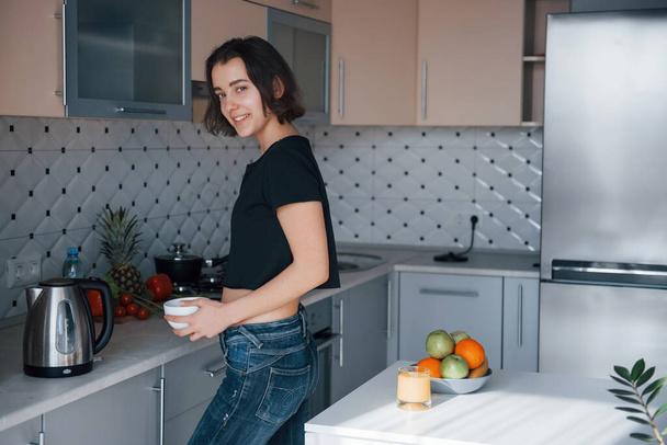 Fashionable interior. Girl in the modern kitchen at home at her weekend time in the morning. - Foto, afbeelding