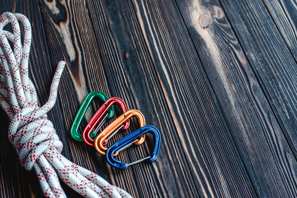 No one. Isolated photo of climbing equipment. Part of carabiner lying on the wooden table. - Zdjęcie, obraz