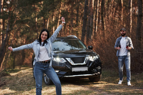 Feeling free. Enjoying the nature. Couple have arrived to the forest on their brand new black car. - Фото, зображення