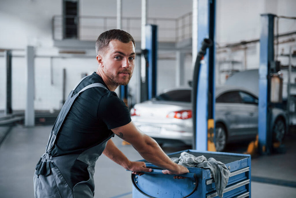Чоловічий механік використовує різні інструменти для ремонту зламаного автомобіля в гаражі
. - Фото, зображення