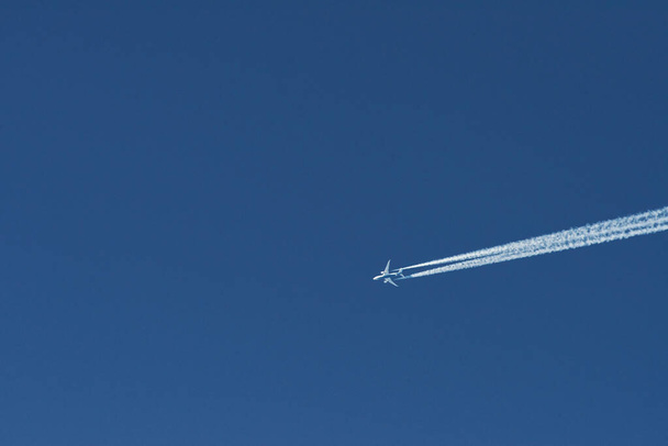 Modern plane flying high in the blue sky at sunny day. Speed and energy. - Photo, Image