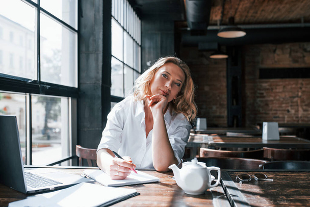 Professional psychologist is ready to help you. Businesswoman with curly blonde hair indoors in cafe at daytime. - Foto, Imagen