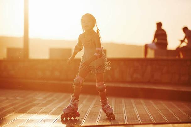 Happy cute kid riding on her roller skates. Unbelievable sunlight. - Foto, Bild