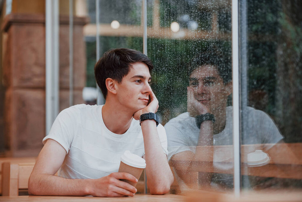 Egy fiatal diák portréja, aki esős napokon ül a kávézóban. Egy személy.. - Fotó, kép
