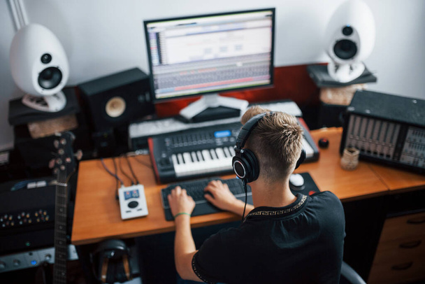 Sound engineer in headphones working and mixing music indoors in the studio. - Фото, зображення