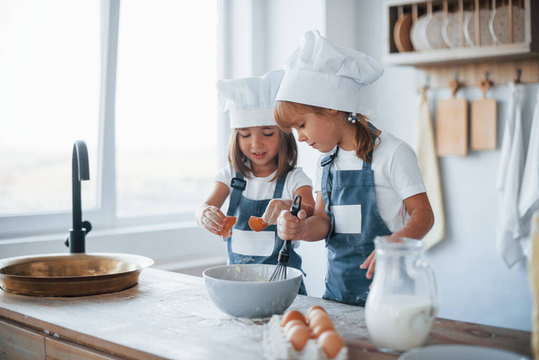 Family kids in white chef uniform preparing food on the kitchen. - Zdjęcie, obraz
