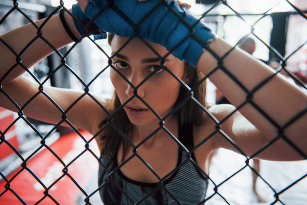 Taking a break. Sportswoman at boxing ring have exercise. Leaning on the fence. - Foto, imagen
