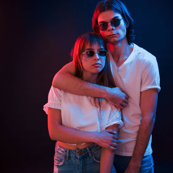 Pure love. Couple standing in dark room with red and blue neon lighting. - 写真・画像