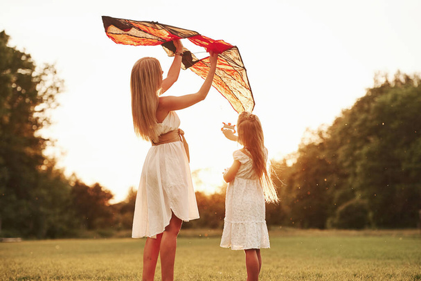 Keep holding it like that. Mother and daughter have fun with kite in the field. Beautiful nature. - Photo, Image