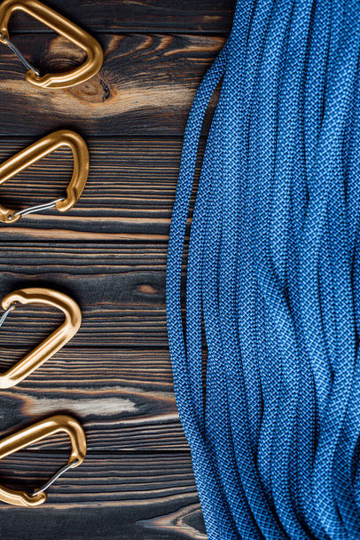 Photographed by designer. Isolated photo of climbing equipment. Part of the carabiner is lying on the wooden table. - Zdjęcie, obraz
