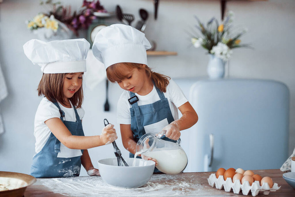 Family kids in white chef uniform preparing food on the kitchen. - Foto, afbeelding