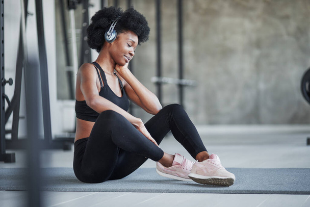 Good mood. African american woman with curly hair and in sportive clothes have fitness day in the gym. - Fotoğraf, Görsel