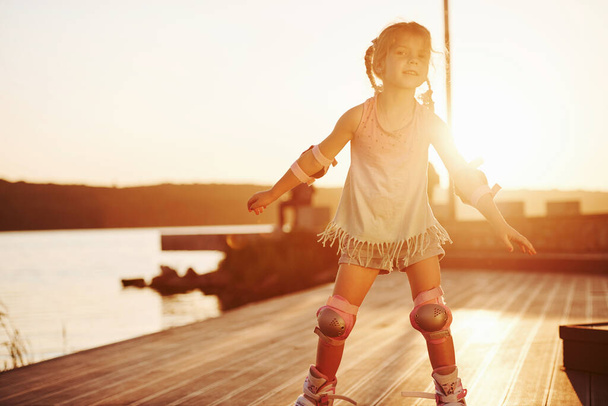 Happy cute kid riding on her roller skates. Unbelievable sunlight. - Фото, зображення