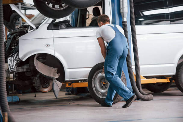 Replacement of tyres. Employee in the blue colored uniform works in the automobile salon. - Foto, Imagem