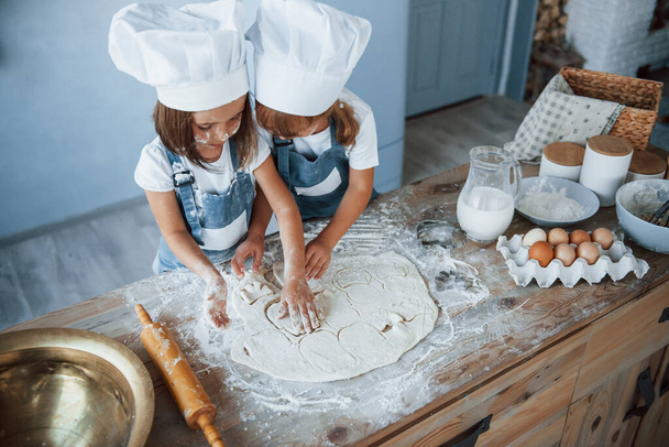 Concentrating at cooking. Family kids in white chef uniform preparing food on the kitchen. - Foto, imagen
