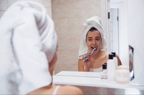 Every day routine with cleaning teeth. In the bathroom. Woman in white towel in head have care of herself. - Foto, imagen