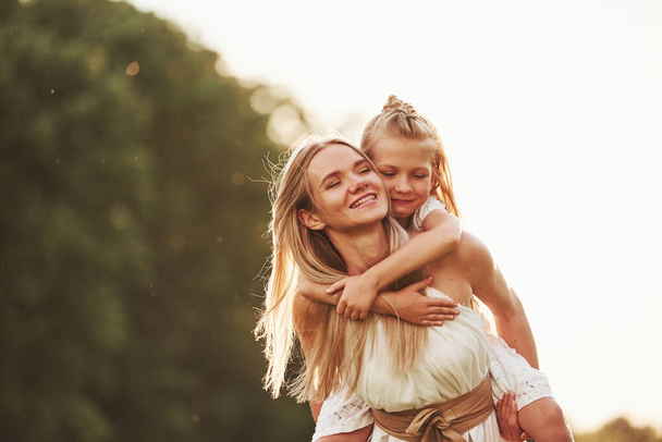 I hold you, don't worry. Mother and daughter enjoying weekend together by walking outdoors in the field. Beautiful nature. - Фото, зображення