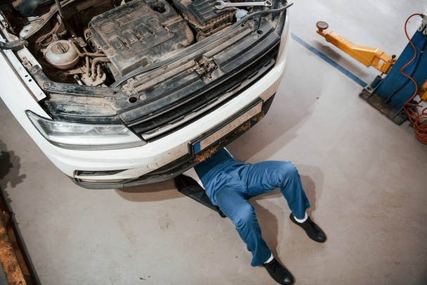 Top view. Employee in the blue colored uniform works in the automobile salon. - Foto, Bild