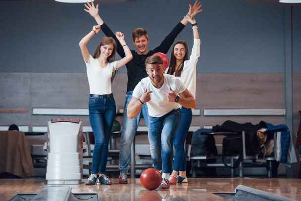 This is win. Young cheerful friends have fun in bowling club at their weekends. - Foto, Bild