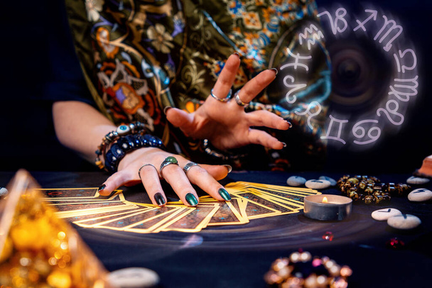 A witch spread out her tarot cards on the table. Hands close-up. The zodiac circle in the upper right corner. The concept of divination and astrology. - Foto, Imagen