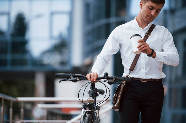 Work do not wait. Businessman in formal clothes with black bicycle is in the city. - Фото, изображение