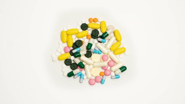 Stos leków w kapsułkach i pigułki o różnych kolorach na białym tle - Zdjęcie, obraz