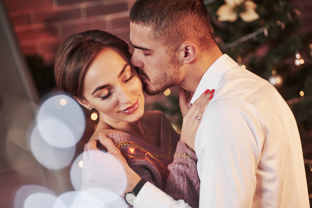 Kiss in the cheek. Nice couple celebrating new year in the new year decorated room. - Foto, Imagem