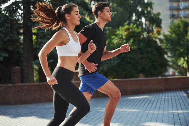 Man and woman have fitness day and running in the city at daytime. - Фото, изображение