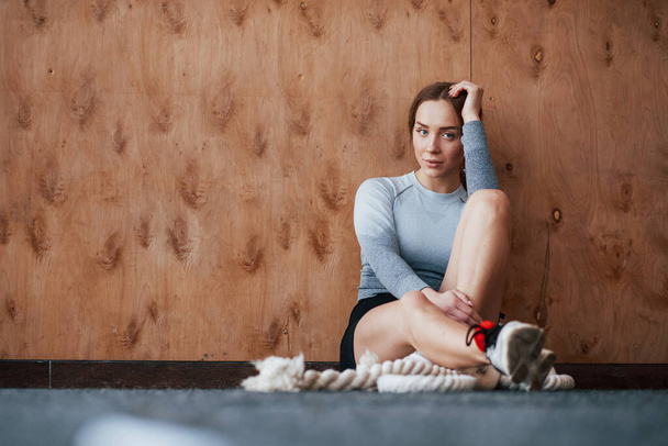 Sitting on the floor. Sportive young woman have fitness day in the gym at morning time. - Fotografie, Obrázek