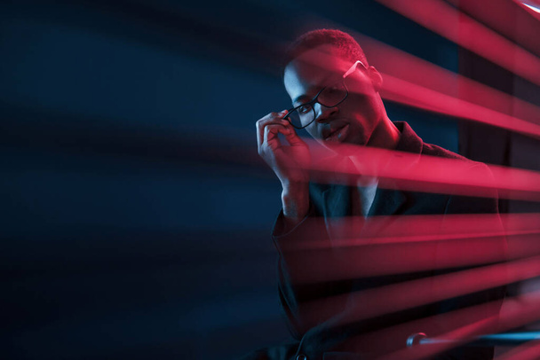 Interesting beams. Futuristic neon lighting. Young african american man in the studio. - Fotoğraf, Görsel